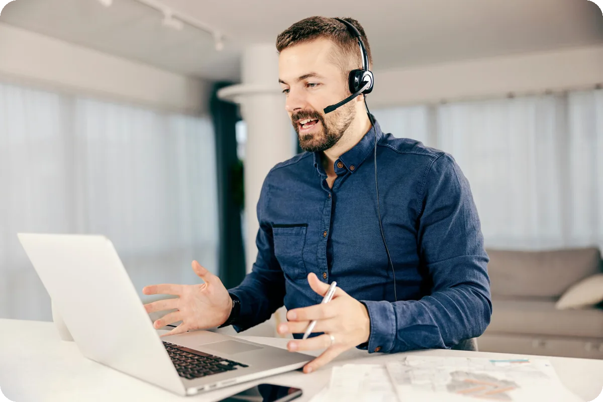Supportmedarbejder med headset i et videoopkald på en bærbar